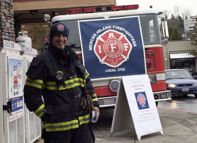 Firefighter Tom Guttu helps out with the Mercer Island Local IFF food drive in front of the Mercer Island Albertsons store on Nov. 24.