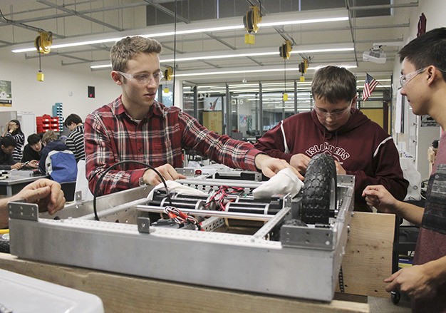 Robotics Club leader Evan Ashley (far left) gets to work on the robot chassis with fellow club members Alex White (center) and Gavin Qu (right) during an after-school session Thursday