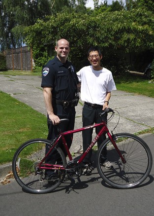 Mercer Island Police Officer Scott Schroeder presents a donated bike to Islander Tynan Power