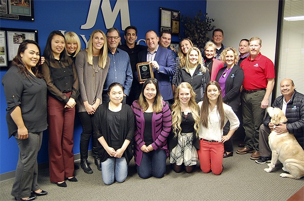 JayMarc employees gather in their office in the Island Corporate Center to show off their Business of the Year award.