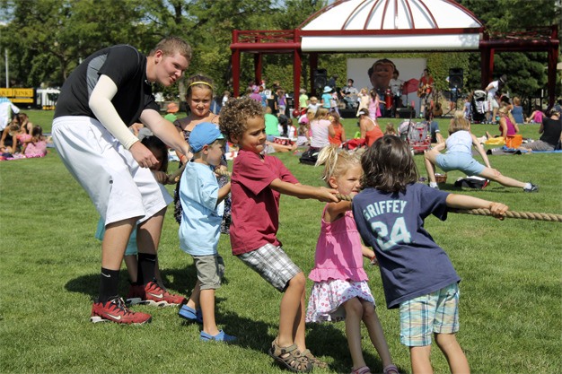 Kids play tug-of-war with Fun Mobile staff member Pete Gordon while the wildly popular Recess Monkey band entertains children in Mercerdale Park on Friday