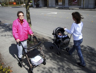 Island senior Ling Lin walks along 77th Avenue S.E. as a young mother passes her with a stroller.