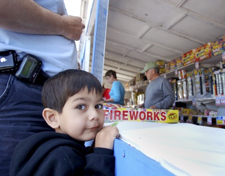 Three-year-old Gareth Tatum peers over the counter of the Kiwanis fireworks stand at the Rite Aid parking lot on June 28 while his father
