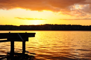 A colorful sunset reflects off the water of Lake Washington at Proctor Landing on Mercer Island Thursday
