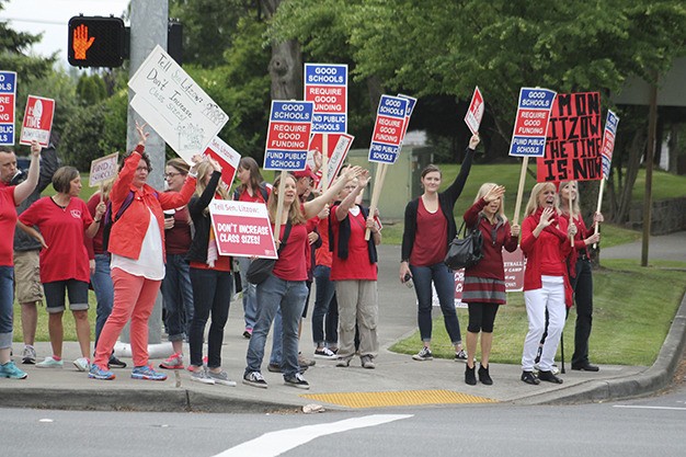 Demonstrators advocating for public education wave signs at the corner of Island Crest Way and S.E. 40th St. Tuesday morning.