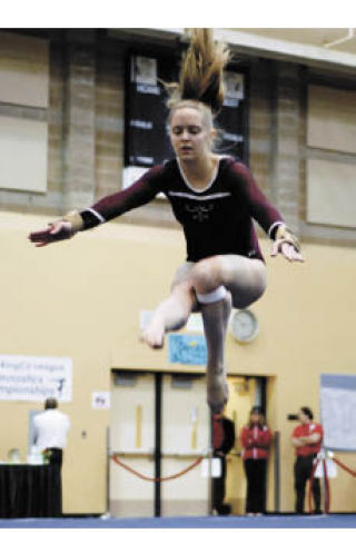 Islander Kendra Johnson competes on floor exercise as coach Lenny Lewis