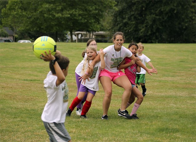 Soccer coach Amy Franke is held back by campers during Friday morning’s soccer match in Mercerdale Park