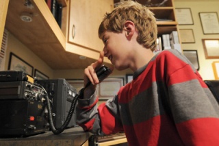 Alex Banbury talks on his father’s ham radio at home. Banbury took a course at the CCMV to earn his radio license this year.