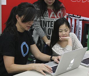IMS parent Jane Bove works with Lakeridge third-grader Abigail Sun on an Hour of Code module Monday