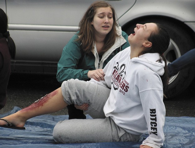 Anais Gralpois helps friend Ally Ritcey during the Mercer Island High School mock DUI demonstration on Friday