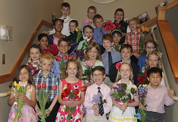 Students at St. Monica School pose on the stairs with flowers before Mass on May 1