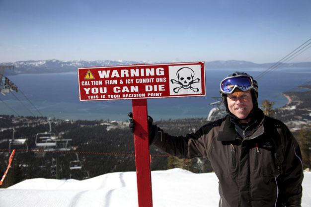 Skier John Naye at Heavenly Resort near Lake Tahoe in California with a sign reminding skiers to tread carefully on the snow.