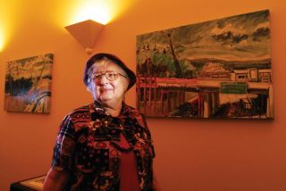 Chad Coleman/Mercer Island Reporter Florence Palmer stands in front of her paintings depicting the construction of I-90 on Mercer Island. The paintings were bought by the city and are on display at the City Hall.