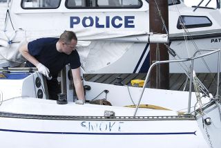 Chad Coleman/Mercer Island Reporter Mercer Island Police Sergeant Lance Davenport surveys a sailboat found adrift at a private dock on Mercer Island in the East Channel.