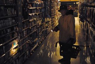 Chad Coleman/Mercer Island Reporter Martha Vaughn of Mercer Island searches for grocery items with a flashlight during a power outage at the Island’s North end QFC on Friday.