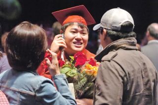 Chad Coleman/Mercer Island Reporter Paul Suh multi-tasks after the ceremony fielding phone calls