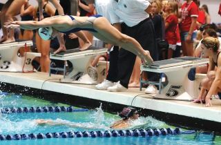 Chad Coleman/Mercer Island Reporter Mercer Island junior Rachel Godfred leaps from the blocks over the head of teammate Jennifer Pak during the 200-yard freestyle relay