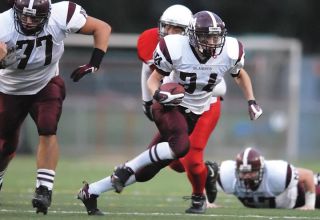 Chad Coleman/Mercer Island Reporter Mercer Island senior Phillip Seda runs through a hole in the defensive line as teammate Jack Gala (77) blocks Sammamish defenders. Seda tied for the second highest single game running total in school history with 226 yards during the game.