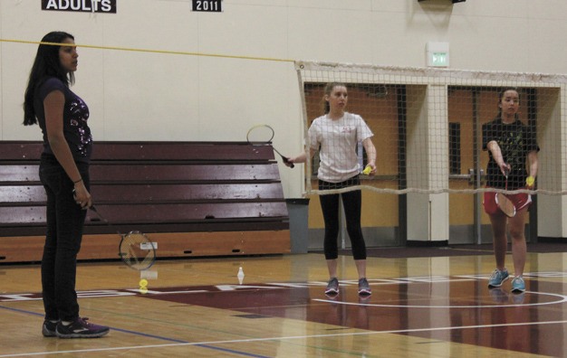 MIHS badminton coach Jessica Roy watches as team members work on their serving.