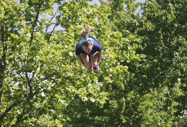 An Action Athletics cheer team member soars among the trees lining 78th Avenue Southeast