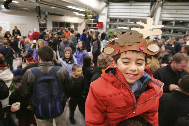 Julius Perez has a reindeer’s-eye view atop his dad’s shoulders at the Firehouse Munch inside the Mercer Island Fire Department’s north end station