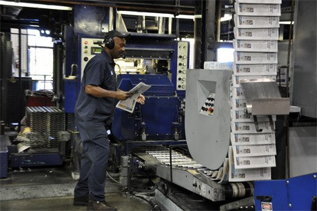 An Everett Printing Facility employee monitors the press as the Wednesday edition of the Mercer Island Reporter rolls along a conveyor belt. Rebecca Mar/Staff Photo