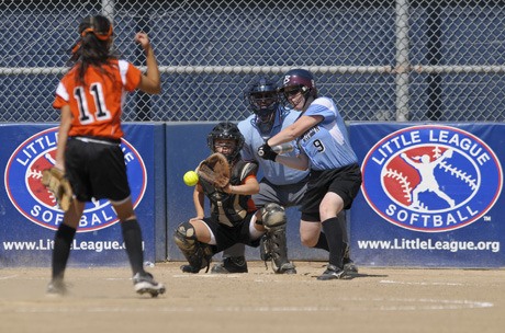 The Washington team’s Brooke Baumgartner (9) hits a single pitch for a single from Southeast’s Amanda Weathers (11) during pool play of the Junior Softball World Series at Everest Park in Kirkland on Tuesday