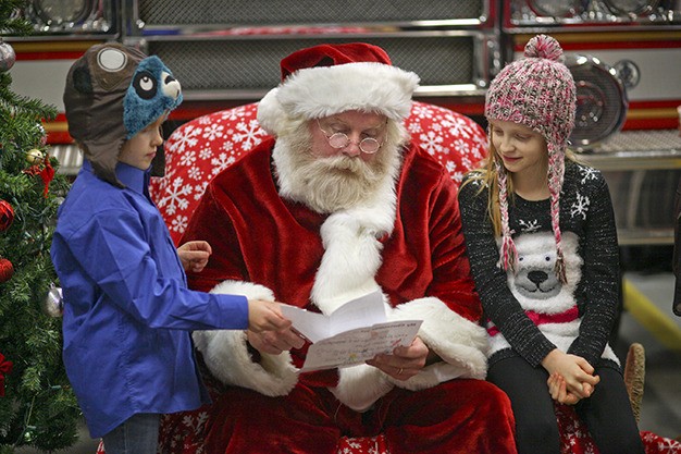 Santa Claus looks over Christmas lists provided by Emma Roberts