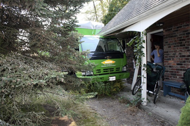 Neighor Tami Szerlip talks on the phone outside the home of Gertrude Hollis on Thursday. A truck belonging to Servpro