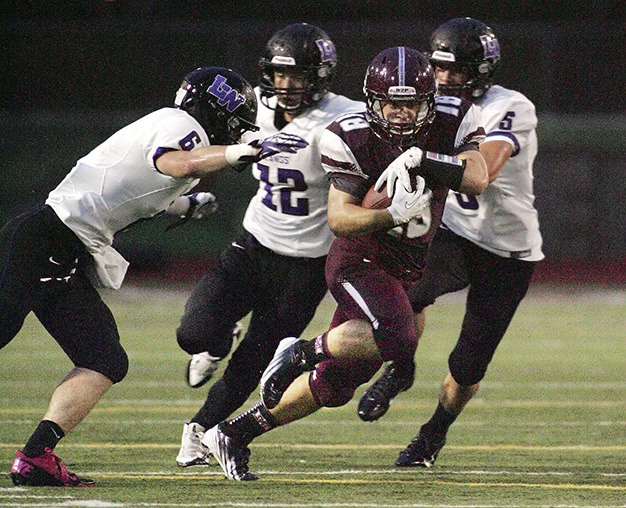 Senior running back Devlin Conway is pursued by Lake Washington’s Scout Callens (left to right)
