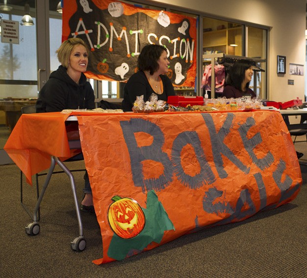 Parents work at the bake sale booth during the MIPA Halloween Party on Saturday