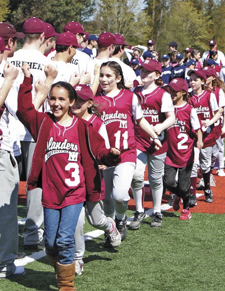 Members of the Mercer Island AAA Island Breeze softball team run past the Mercer Island High School baseball team on Saturday morning at the South Mercer Playfields as part of the opening day ceremonies.
