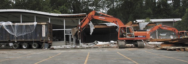 Crews work on demolishing the old Safeway building in preparation for the new residential and retail project