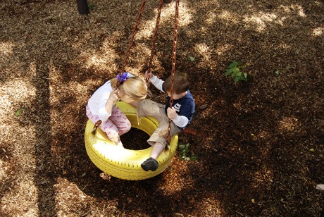 A couple of Mercer Island kids enjoy the sunshine while swinging on a bright yellow tire swing at West Mercer Elementary.
