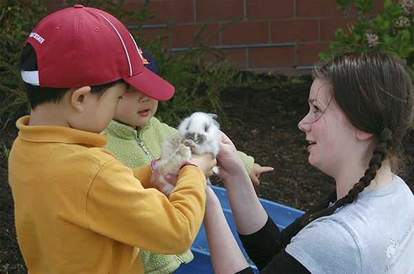 Island youngsters play with a baby bunny at the Leap for Green sustainability fair on April 16 at the Community and Event Center.