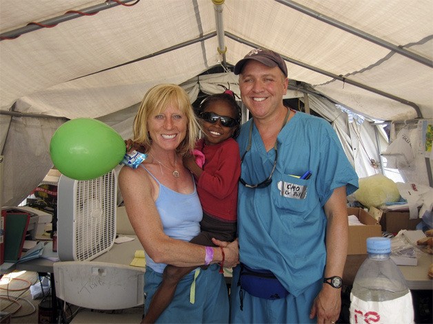 Mercer Island residents Bill and C.C. Crenshaw smile with a little Haitian girl in the Project Medishare hospital. The little girl would later die from cancer.