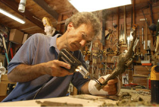 Pepper Kaminoff crafts a wax sculpture with a soldering iron in his garage workshop on Mercer Island Monday
