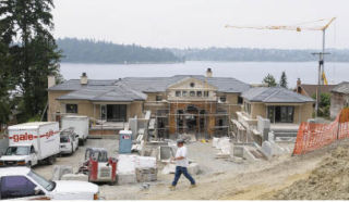 A construction worker walks by a waterfront home under construction on Boulevard Place. City officials said it is likely the biggest home built on the Island.