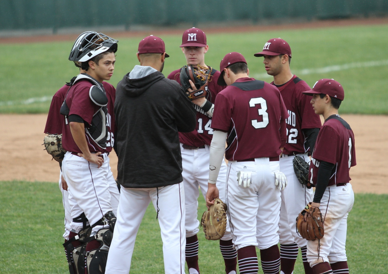 Members of the Mercer Island baseball team huddle with coach Dominic Woody during their regional matchup against Southridge Saturday in Kelso. The Suns beat the Islanders 11-1 (photo courtesy of Gregg Petrie).