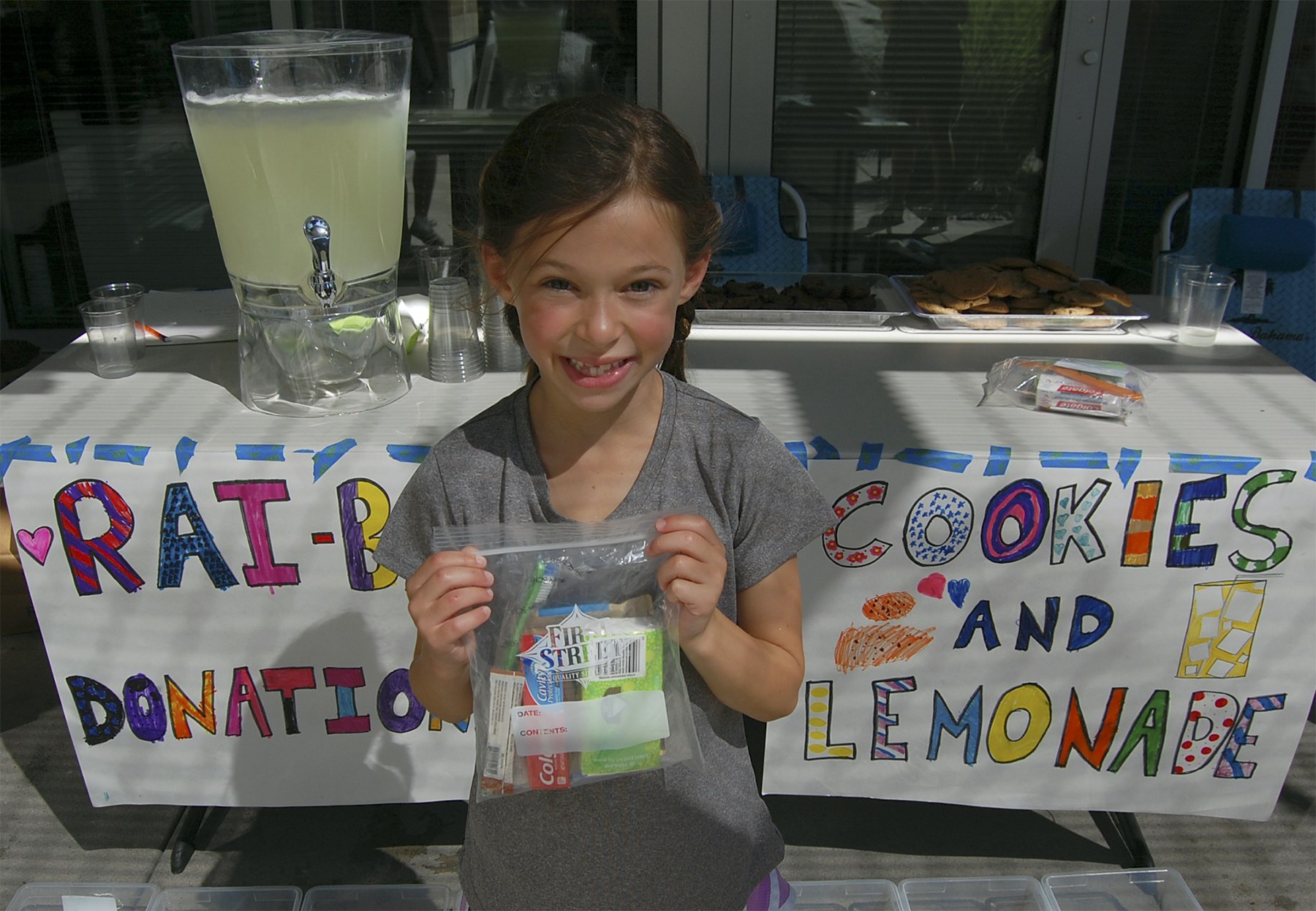 Rainey Rosenwald poses with one of the "Rai Bags" she assembled from donations to her lemonade stand outside Coldwell Banker Bain Thursday. Katie Metzger/staff photo