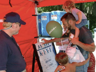 KIXI operations manager Dan Murphey watches as Islanders play a game in the station’s tent at Summer Celebration last year.