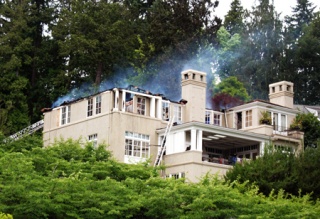 A house on East Mercer Way belonging to Beecher's Cheese and Bennett's Pure Food Bistro owner Kurt Dammeier smolders hours after the roof caught fire the morning of July 4.