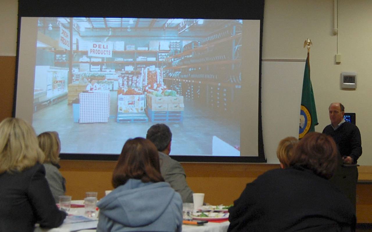 Costco CFO Richard Galanti shows the Mercer Island Chamber a photo of an old Costco layout, with the deli products next to the tires, at the Dec. 1 meeting. Katie Metzger/staff photo