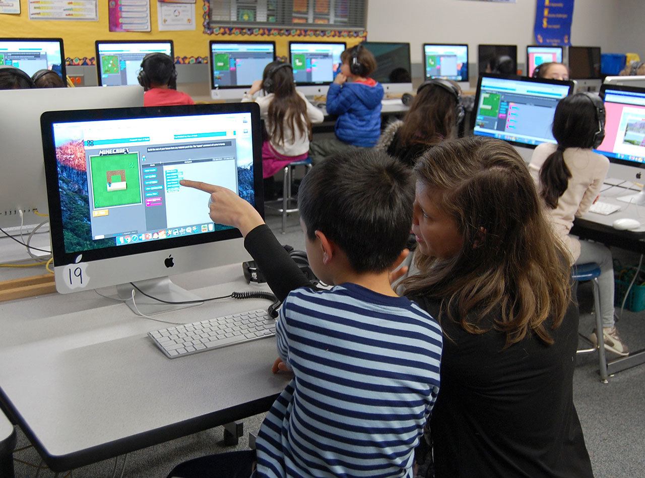 TOSA Kara Millsap helps a second-grader at West Mercer Elementary complete a “progression puzzle” as part of the national Hour of Code event. Katie Metzger/staff photos