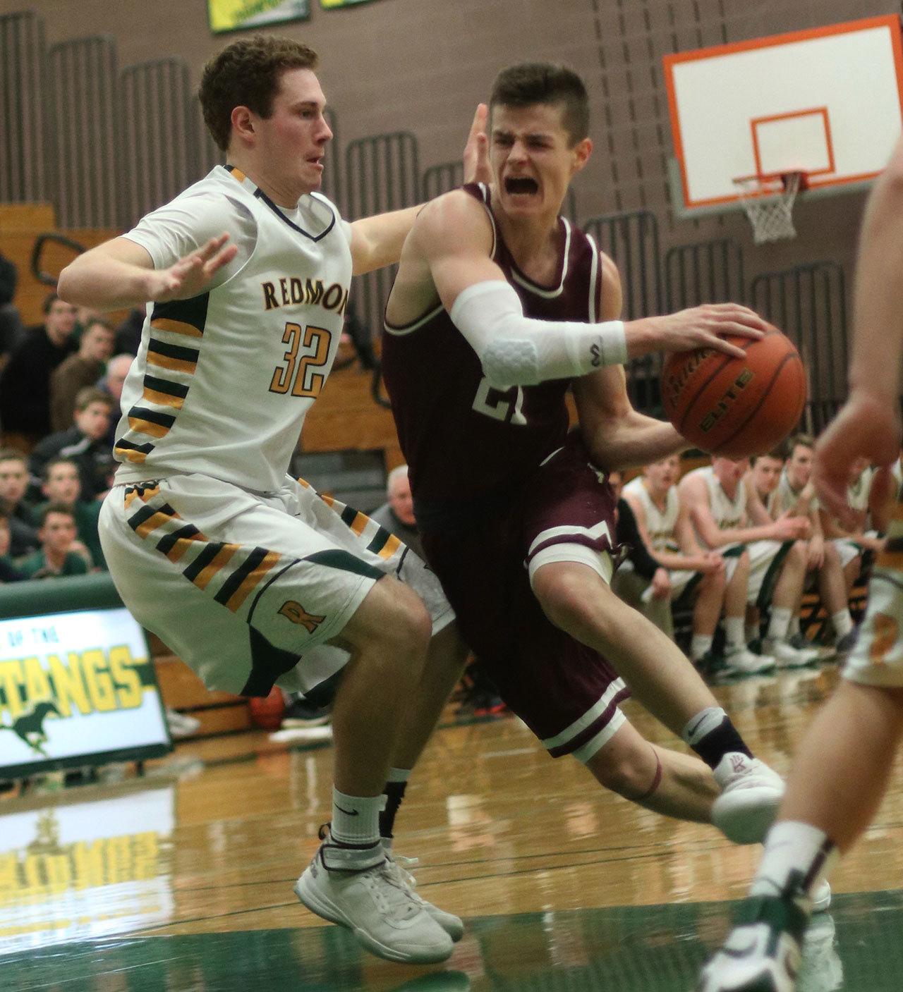 Mercer Island’s Shain Scott, right, drives past Redmond’s Kellen Shoup on Tuesday at Redmond High School. Andy Nystrom/Redmond Reporter.