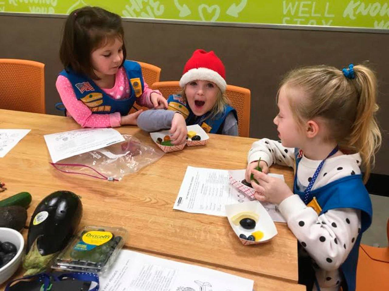 Kindergartners and Girl Scout Daisies Grace Zahler, Lucy Sternberg and Milana Jaeger try different colored foods at New Seasons on Dec. 5 as part of an “eat the rainbow” challenge to earn their “courageous and strong” petal. Photo courtesy of Ashley Sternberg