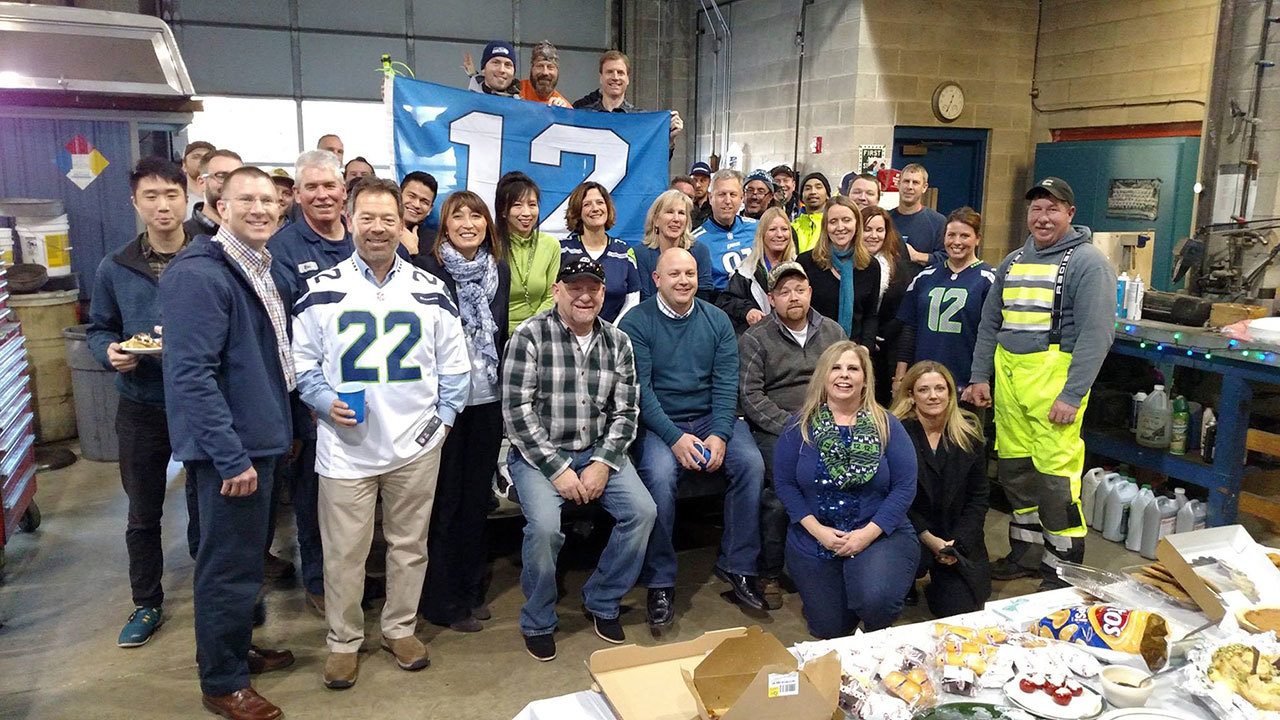 City employees wear Seahawks gear and hold a 12th man flag to support the team before its game against Detroit last week. Photo courtesy of MIPD