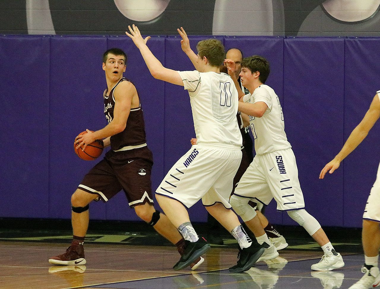 Mercer Island’s Griffin Emanuels looks to pass against Lake Washington defenders Griffin Barker (11) and Sam Linsky Friday at Lake Washington High School. The Kangs rallied to beat the Islanders 61-60 (Joe Livarchik/staff photo).