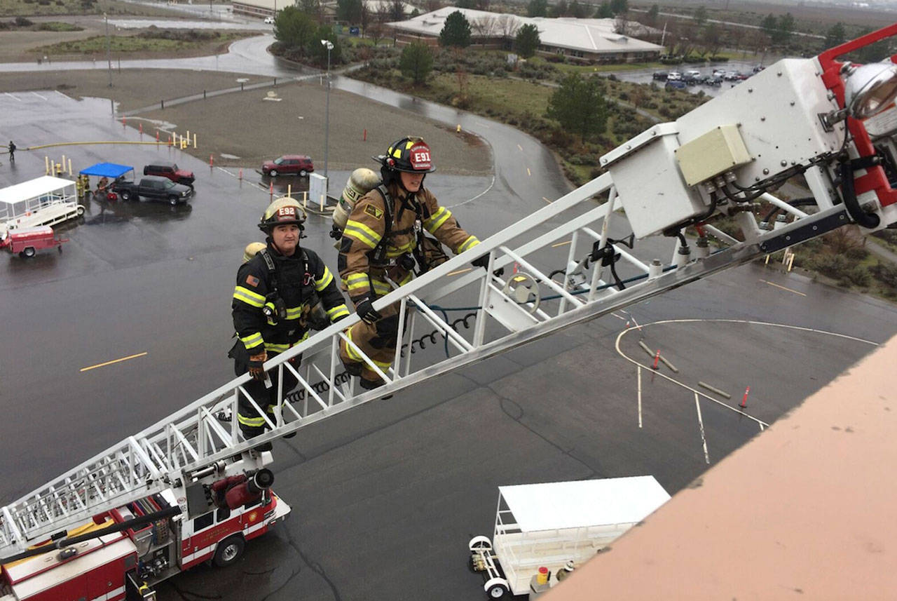 City Manager Julie Underwood and Mercer Island firefighter Ken Knott climb up a ladder truck. Photo courtesy of Ken Knott