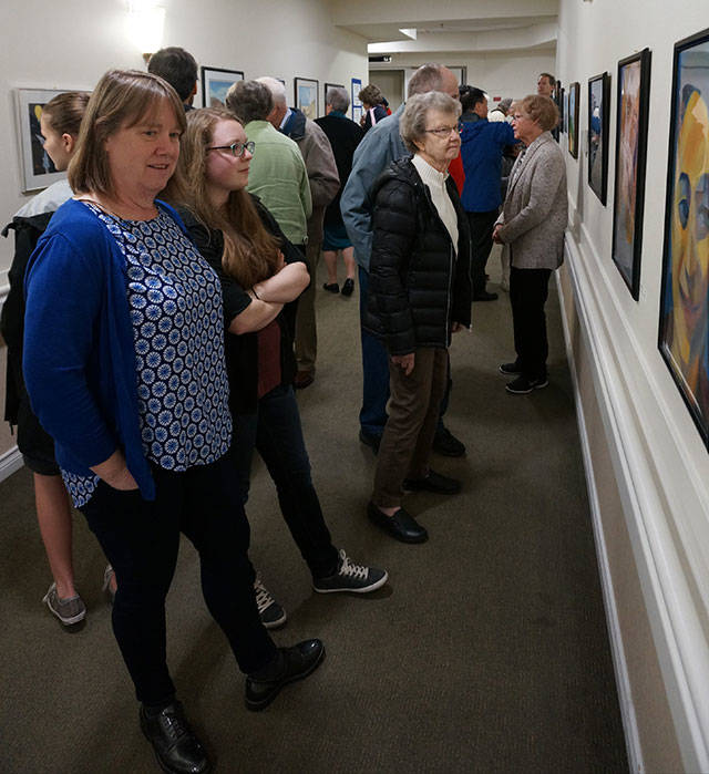 Artist and MIHS senior Rebecca Bone and her mother Carolyn (left) admire portraits at the MIVAL Jr. Lighthouse Gallery art show at Covenant Shores. Photo courtesy of Brandon Hill